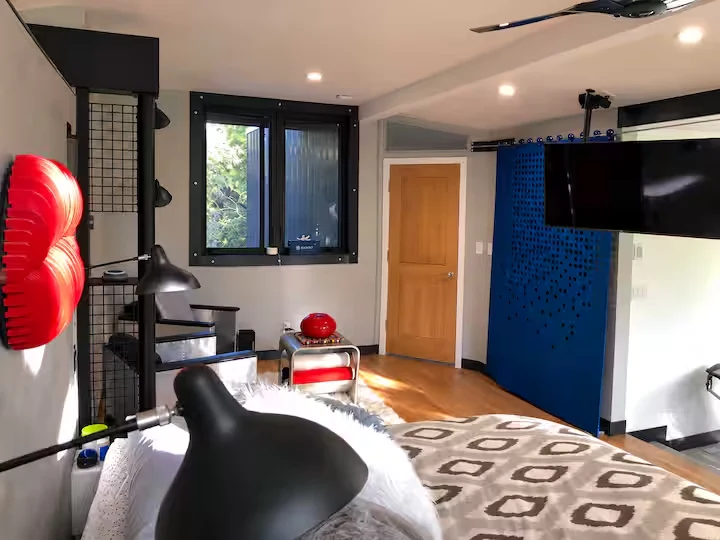 Bedroom sitting corner with metal armchairs, red accent table, artwork and blue sliding screen