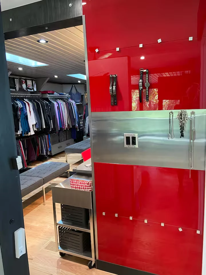 Glossy red dressing-room cabinetry with stainless steel panels beside mirrored closet entrance