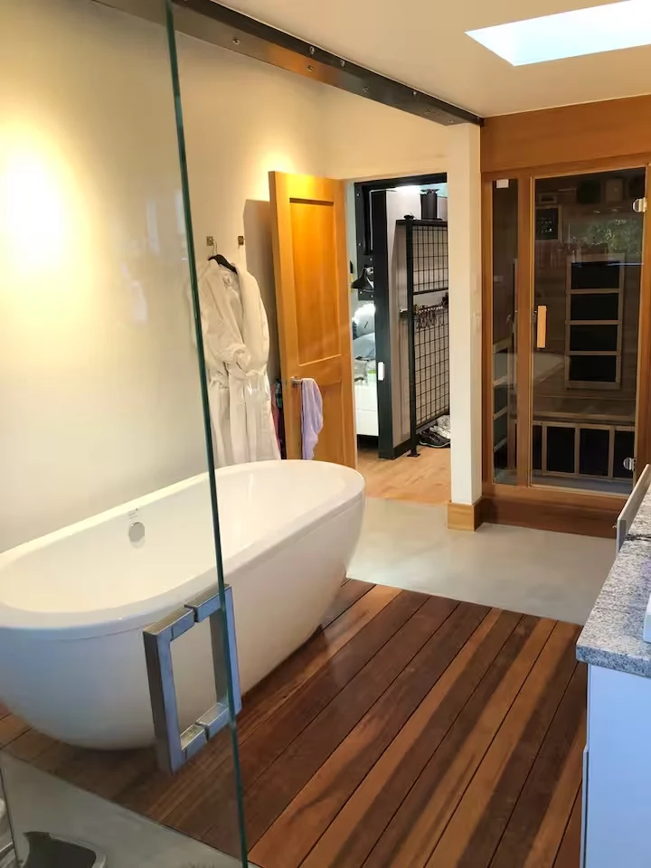 Primary bathroom with soaking tub, wood floor accents and wood-framed infrared sauna