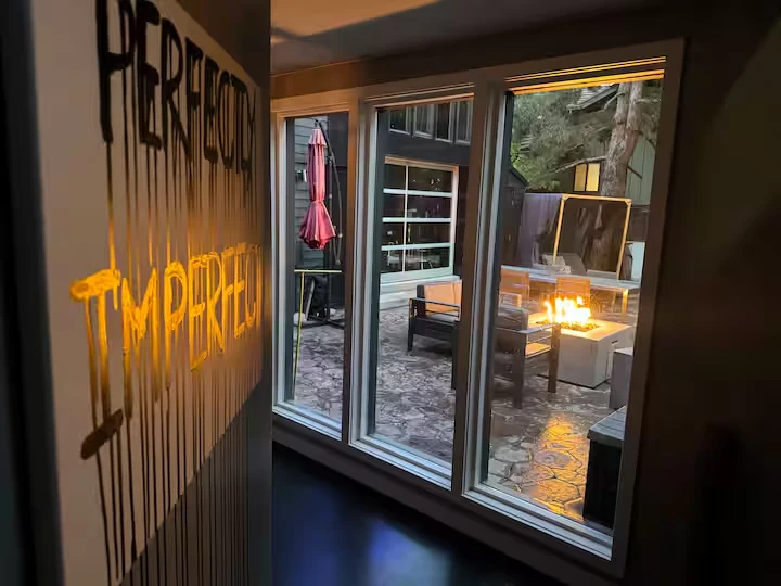 Interior window overlooking the courtyard fire pit beside Perfectly Imperfect wall artwork