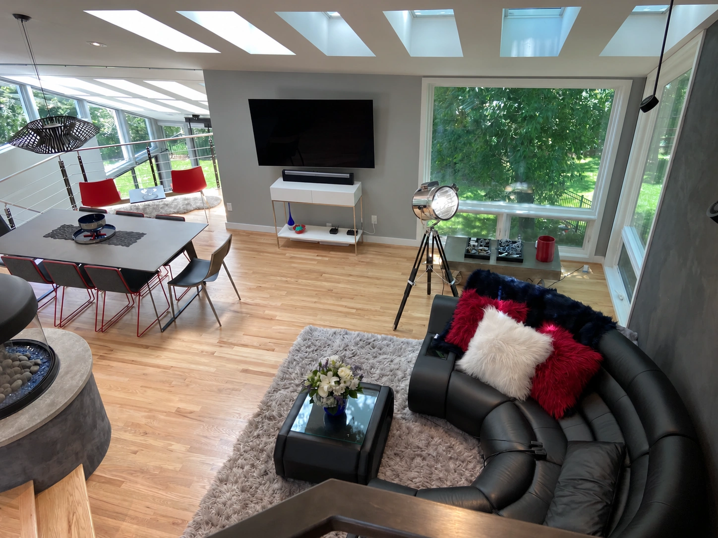 Overhead view of the living room with curved black sofa, dining table, skylights and large windows