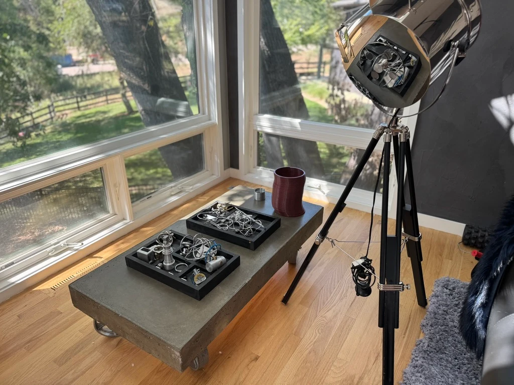 Tripod spotlight and wire puzzles on a concrete table beside the living room windows